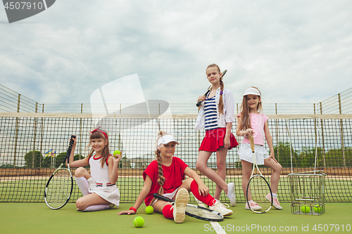 Image of Portrait of group of girls as tennis players holding tennis racket against green grass of outdoor court