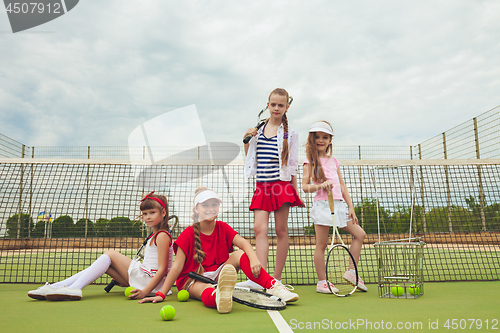 Image of Portrait of group of girls as tennis players holding tennis racket against green grass of outdoor court