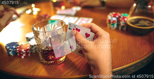 Image of Side view photo of friends sitting at wooden table. Friends having fun while playing board game.