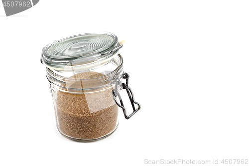 Image of Brown cane sugar in glass jar isolated on white background. 