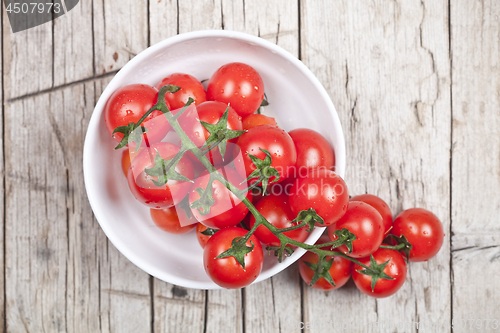 Image of Fresh tomatoes in white bowl on rustic wooden table. 