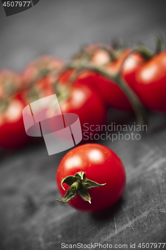 Image of Fresh organic cherry tomatoes bunch closeup on black board.