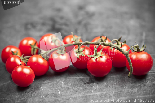 Image of Fresh organic cherry tomatoes bunch closeup on black board.