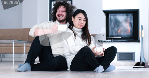 Image of multiethnic romantic couple  in front of fireplace