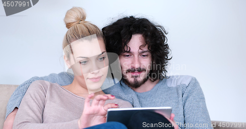 Image of couple relaxing at  home with tablet computers
