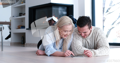 Image of Young Couple using digital tablet on the floor