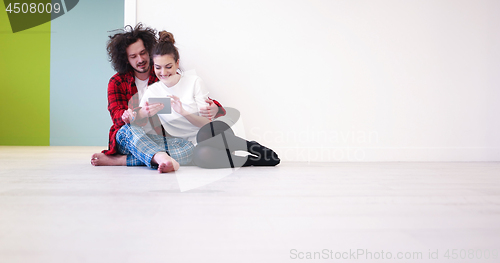 Image of Young Couple using digital tablet on the floor