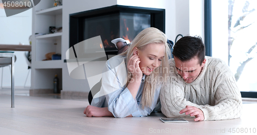 Image of Young Couple using digital tablet on the floor