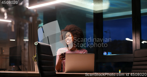 Image of black businesswoman using a laptop in night startup office