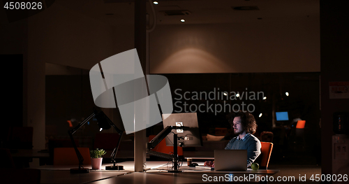 Image of man working on computer in dark office