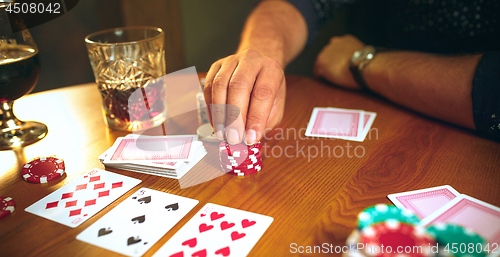 Image of Side view photo of friends sitting at wooden table. Friends having fun while playing board game.