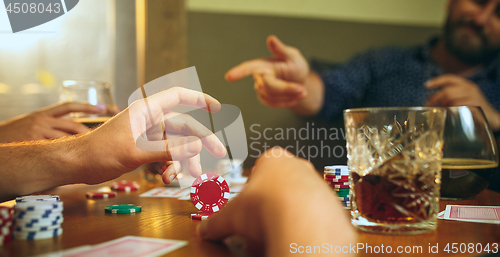 Image of Side view photo of friends sitting at wooden table. Friends having fun while playing board game.