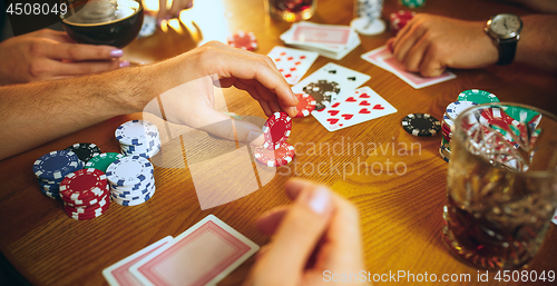 Image of Side view photo of friends sitting at wooden table. Friends having fun while playing board game.