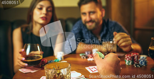 Image of Friends sitting at wooden table. Friends having fun while playing board game.