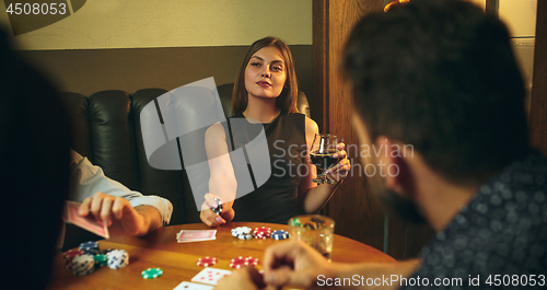 Image of Friends sitting at wooden table. Friends having fun while playing board game.