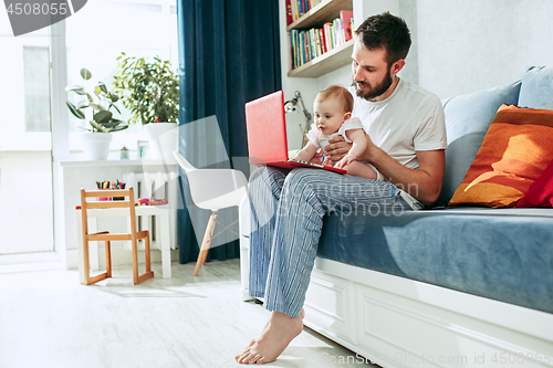 Image of Proud father holding his baby daughtesr at home