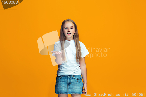 Image of Beautiful female half-length portrait on orange studio backgroud. The young emotional teen girl