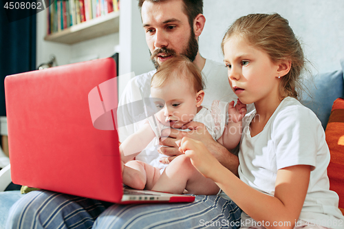 Image of Proud father holding his baby daughters at home