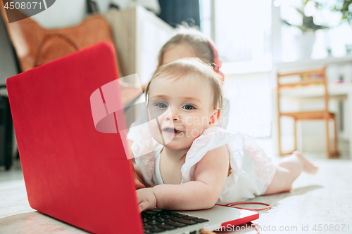 Image of Portrait of little baby girl looking at camera with a laptop
