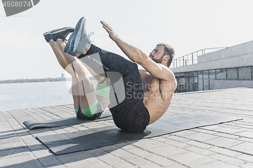 Image of Fit fitness woman and man doing stretching exercises outdoors at city