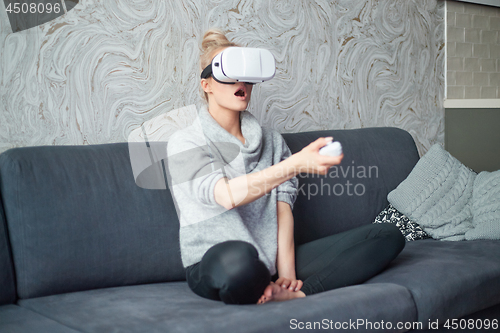 Image of Young woman watching videos or playing with VR glasses on head