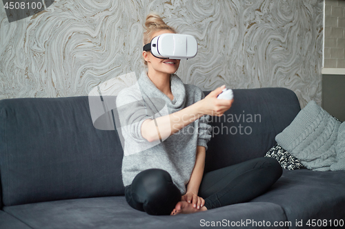 Image of Young woman watching videos or playing with VR glasses on head