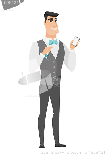 Image of Caucasian groom holding a mobile phone.