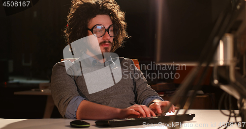 Image of man working on computer in dark office