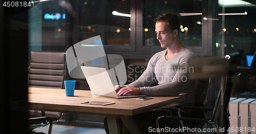 Image of man working on laptop in dark office