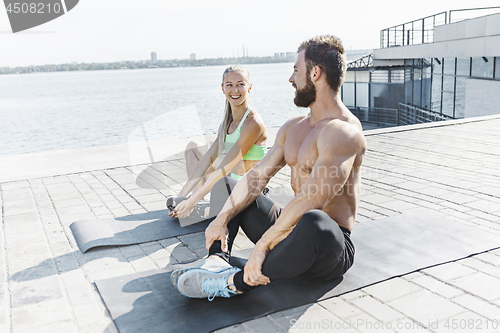 Image of Fit fitness woman and man doing stretching exercises outdoors at city