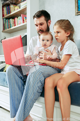 Image of Proud father holding his baby daughters at home