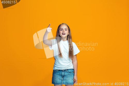 Image of Beautiful female half-length portrait on orange studio backgroud. The young emotional teen girl