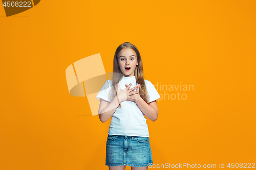 Image of Beautiful teen girl looking suprised isolated on orange