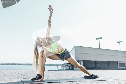 Image of Fit fitness woman doing stretching exercises outdoors at park