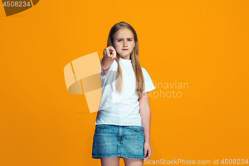 Image of The happy teen girl pointing to you, half length closeup portrait on orange background.