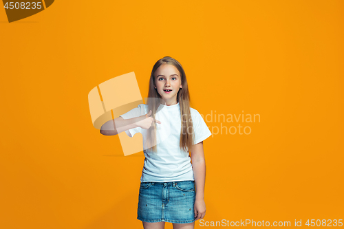 Image of Beautiful female half-length portrait on orange studio backgroud. The young emotional teen girl
