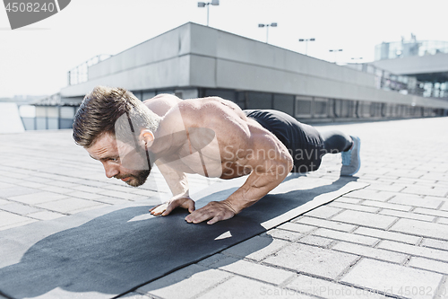 Image of Fit fitness man doing fitness exercises outdoors at city