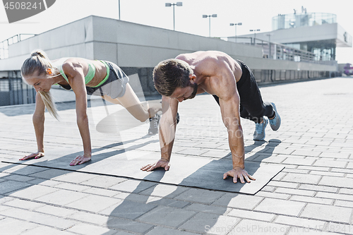 Image of Fit fitness woman and man doing fitness exercises outdoors at city