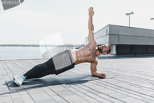 Image of Fit fitness man doing fitness exercises outdoors at city