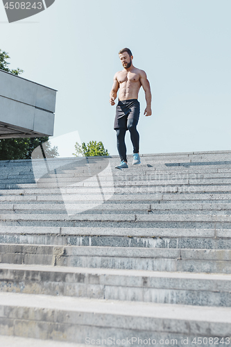 Image of Fit man doing exercises outdoors at city