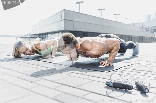 Image of Fit fitness woman and man doing fitness exercises outdoors at city