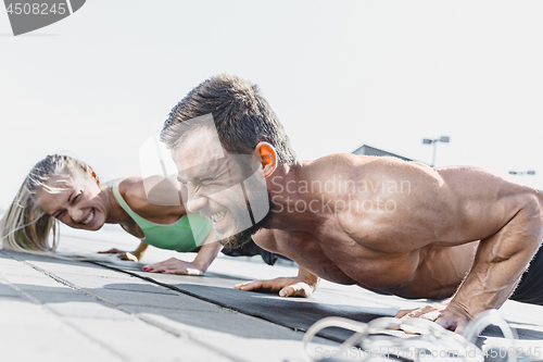 Image of Fit fitness woman and man doing fitness exercises outdoors at city