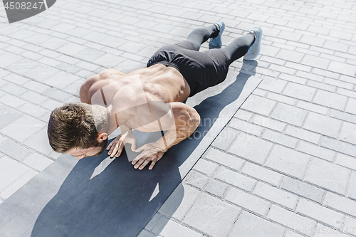 Image of Fit fitness man doing fitness exercises outdoors at city
