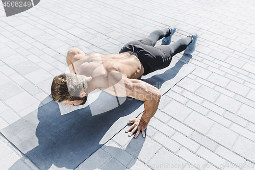 Image of Fit fitness man doing fitness exercises outdoors at city