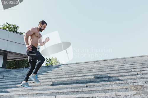 Image of Fit man doing exercises outdoors at city