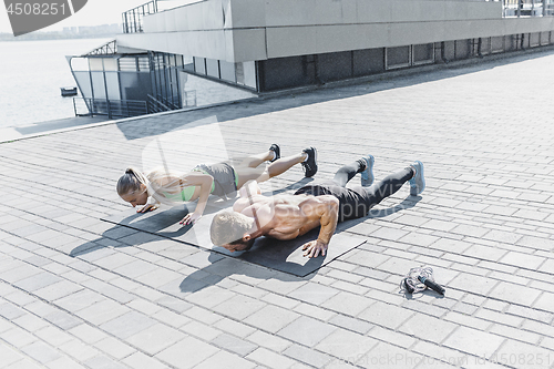 Image of Fit fitness woman and man doing fitness exercises outdoors at city