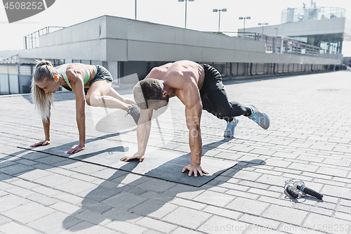 Image of Fit fitness woman and man doing fitness exercises outdoors at city