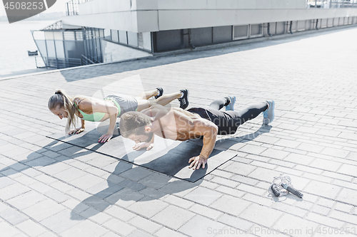 Image of Fit fitness woman and man doing fitness exercises outdoors at city