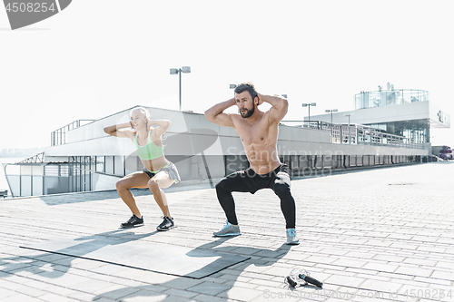 Image of Fit fitness woman and man doing fitness exercises outdoors at city