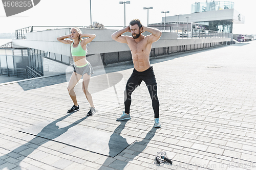 Image of Fit fitness woman and man doing fitness exercises outdoors at city